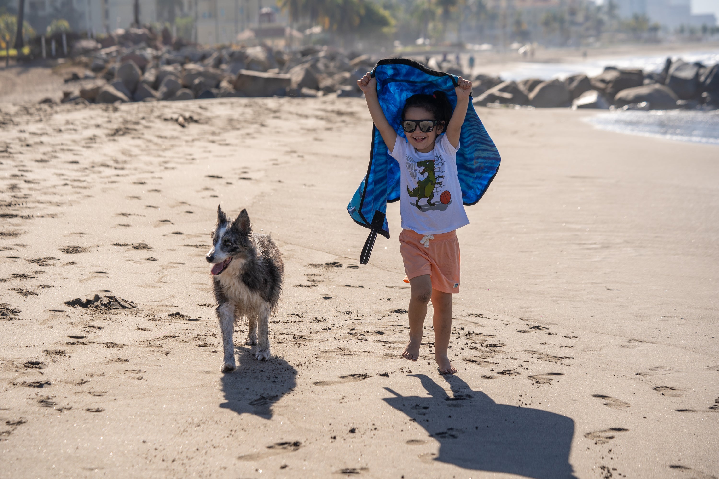 Boy running with his dog while Beach Leash flows like a cape